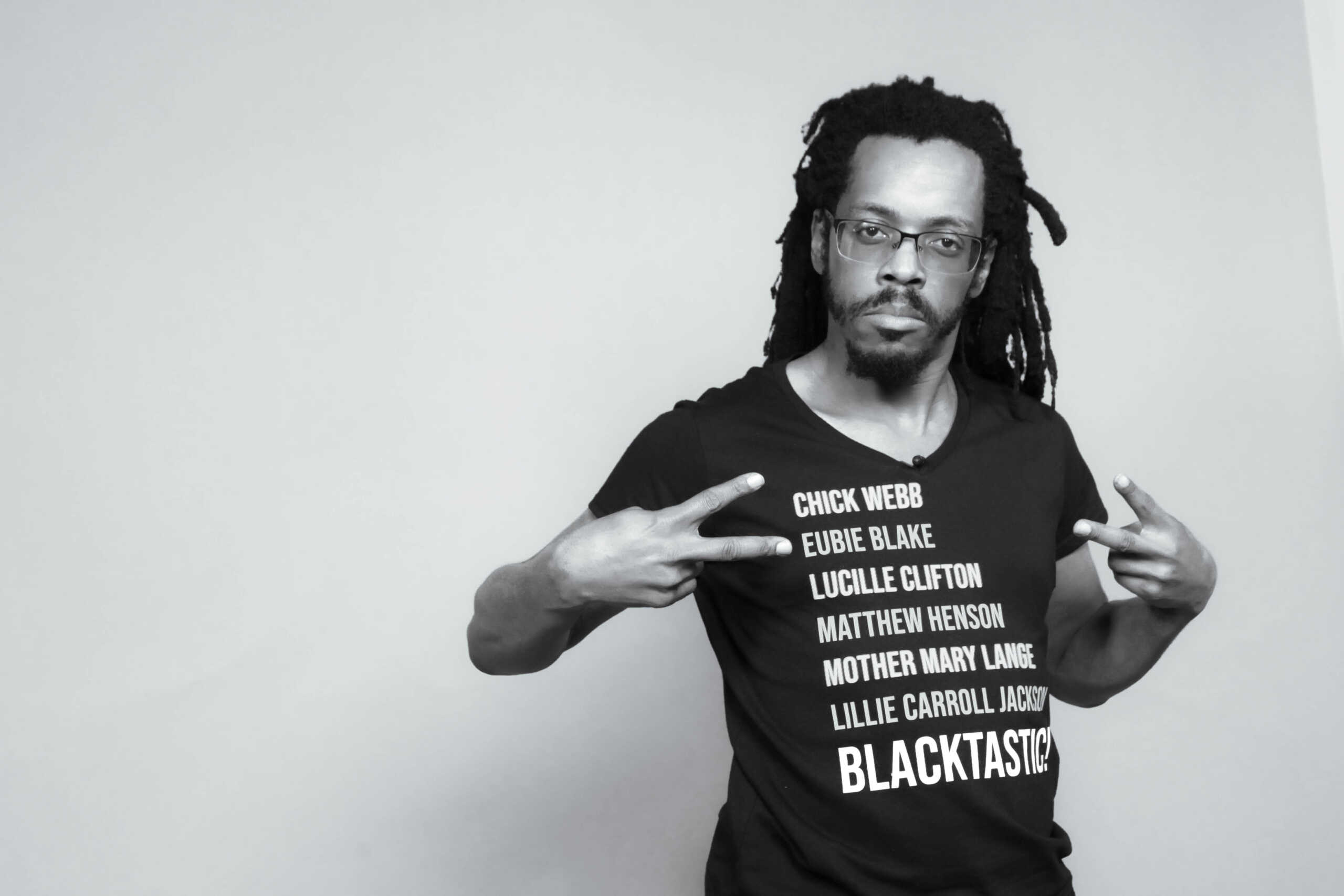 Black and white photograph of Baba Bomani in Blacktastic t-shirt.